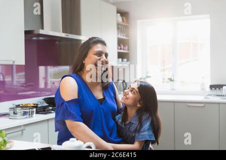 Glückliche Mutter und Tochter umarmten in der Küche Stockfoto