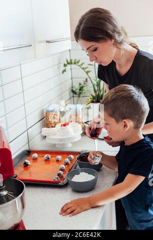 Schöne Frau Mutter und Sohn zusammen kocht süße Kuchen in der Küche Stockfoto