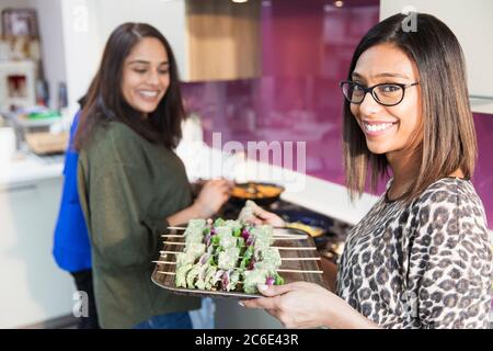 Portrait lächelnde indische Frau mit Tablett von Kebabs in der Küche Stockfoto