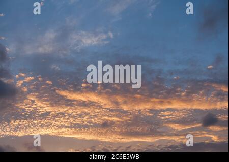 Untergehende oder aufgehende Sonne färbt Stratocumulus Cumulus als dramatische Schichten von Wolken reflektieren verschiedene Sonnenstrahlen aufgrund der Höhe Stockfoto