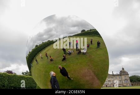 Der Künstler Anish Kapoor blickt vor der Eröffnung seiner größten britischen Ausstellung von Outdoor-Skulpturen in Houghton Hall, King's Lynn, in seine Skulptur 'Sky Mirror'. Stockfoto