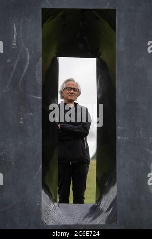 Der Künstler Anish Kapoor blickt vor der Eröffnung seiner größten britischen Ausstellung von Outdoor-Skulpturen in der Houghton Hall, King's Lynn, durch eine seiner Skulpturen. Stockfoto