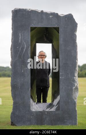 Der Künstler Anish Kapoor blickt vor der Eröffnung seiner größten britischen Ausstellung von Outdoor-Skulpturen in der Houghton Hall, King's Lynn, durch eine seiner Skulpturen. Stockfoto