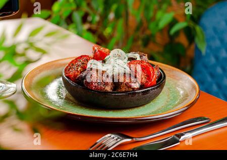 Gegrilltes würziges grillfleisch auf Spieße mit gebackenen Tomaten und frischen Zwiebeln in rustikaler Schüssel serviert. Kaukasische Küche. Stockfoto