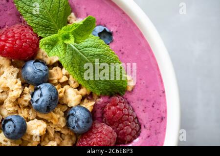 Smoothie Schüssel mit Müsli und Beeren mit Minze verziert. Draufsicht, Nahaufnahme. Stockfoto