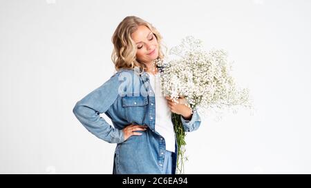 Stilvolle junge blonde Frau mit einem Bouquet von Gypsophila. Porträt auf weißem Hintergrund. Happy Girl mit einem Blumenstrauß, Blumenlieferung. Stockfoto