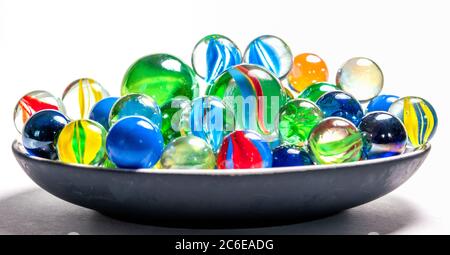 Bunte Murmeln in einer Schale vor weißem Hintergrund Stockfoto