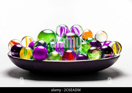 Bunte Murmeln in einer Schale vor weißem Hintergrund Stockfoto
