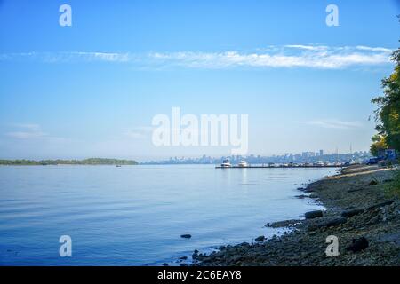 Blick auf den großen Fluss, über den man mit Booten und der Stadt den Pier sehen kann. Stockfoto