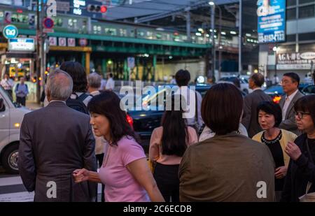 Menschen in der Straße von Shimbashi, Tokyo, Japan bei Dämmerung mit Shimbashi Bahnhof im Hintergrund. Stockfoto