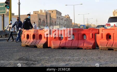 Kuwait-Stadt, Kuwait. Juli 2020. Ein Polizist entfernt Straßensperren vom Eingang zum Jleeb Al-Shuyoukh Bereich nach der Aufhebung der Sperrbeschränkungen, in Farwaniya Governorate, Kuwait, 9. Juli 2020. Die kuwaitische Regierung hob am Donnerstag die Sperre in den Gebieten Jleeb Al-Shuyoukh und Mahboula auf. Die Sperre wurde den beiden im Ausland dominierten und stark besiedelten Gebieten seit dem 6. April auferlegt. Quelle: Asad/Xinhua/Alamy Live News Stockfoto