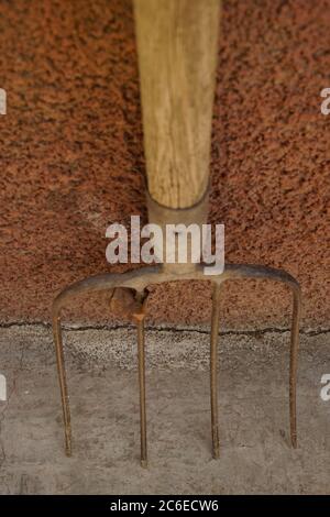 Alte Pitchfork stehen auf dem Steinboden. Stockfoto