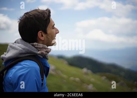 Ein junger Tourist, der auf einem Felsen sitzt. Er ist auf dem Gipfel der Stara Planina (Balkan-Gebirge) und genießt die Aussicht. Stockfoto