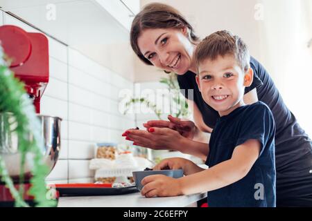 Schöne Frau Mutter und Sohn zusammen kocht süße Kuchen in der Küche Stockfoto