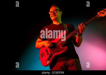 Junge kaukasische inspirierte und expressive Musiker, Gitarrist auf gradienten farbigen Hintergrund in Neonlicht. Konzept der Musik, Hobby, Festival, Kunst. Fröhliche Künstler, bunt, helles Porträt. Stockfoto