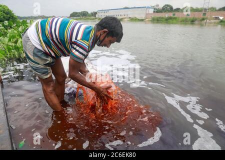 Tongi, Bangladesch. Juli 2020. Ein Mann aus Bangladesch wäscht Plastikmüll, der zum Transport von Chemikalien verwendet wurde, im Wasser des Turag-Flusses, bevor er ihn recycelt, in Tongi, nahe Dhaka, Bangladesch, 9. Juli 2020. Quelle: Suvra Kanti das/ZUMA Wire/Alamy Live News Stockfoto