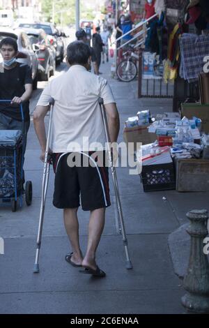 Mann läuft mit Krücken am East Broadway in Chinatown, NYC. Stockfoto