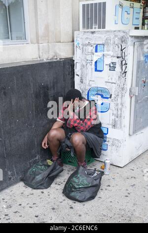 Müde junger Mann schlafen sitzen auf der Church Avenue in Brooklyn, New York. Stockfoto