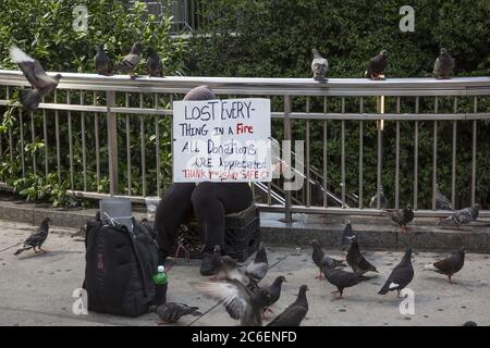 Frau, die alles in einem Feuer verloren hat, sagt sie, bittet um Hilfe, am Columbus Circle am Central Park in New York City zu sitzen. Stockfoto