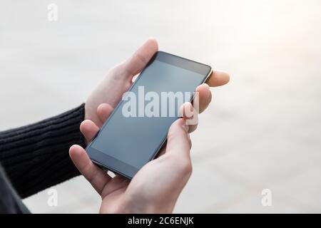 Der Mensch benutzt sein Mobiltelefon im Freien. Hände des Mannes halten Smartphone mit leerem Kopieplatz Bildschirm für Ihre Informationen Inhalt. Stockfoto