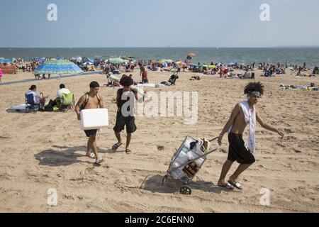 Mit dem Sommer hier beginnt der Strand von Coney Island trotz der Covid-19 Pandemie zu füllen. Junge Männer verkaufen kalte Getränke am Strand. Die Menschen werfen ihre Masken in der Regel, während am Strand. Brooklyn, New York Stockfoto