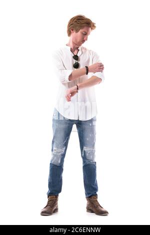 Ernst junge lässig gut gekleidet Mann Reinigung weißen Hemd Ärmel immer angezogen. Ganzkörperlänge isoliert auf weißem Hintergrund. Stockfoto