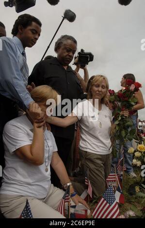 Crawford, Texas, 28. August 2005: Die Antikriegsaktivistin Cindy Sheehan (links) und Jane Bright (rechts) knieten vor einer Ausstellung von Kreuzen, während Reverend Al Sharpton aus New York (schwarz) in Camp Casey II nahe der Ranch des US-Präsidenten George W. Bush zusieht ©Bob Daemmrich Stockfoto