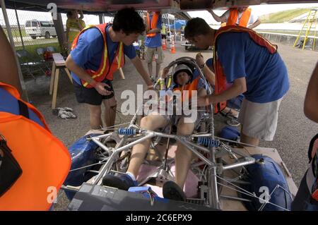 College Station, Texas, USA, 15. Juli 2005: Eine Boxenmannschaft senkt die Sonnenkollektorplatte auf das Cockpit und den Fahrer eines Solarwagens vor dem Start des North American Solar Challenge 2.500 km langen Solarwagenrennens von Austin, Texas, nach Calgary, Alberta, Kanada. Die 10-tägige Veranstaltung umfasst 22 College- und Universitätsteams aus den USA ©Bob Daemmrich Stockfoto