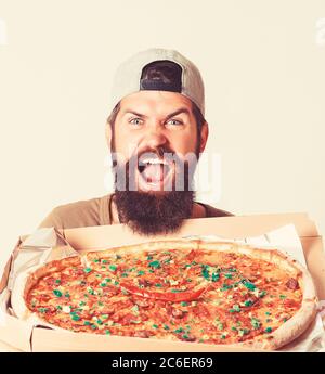 Junger Mann bietet Pizza Diavola. Pizzalieferer hält Box in den Händen. Stockfoto