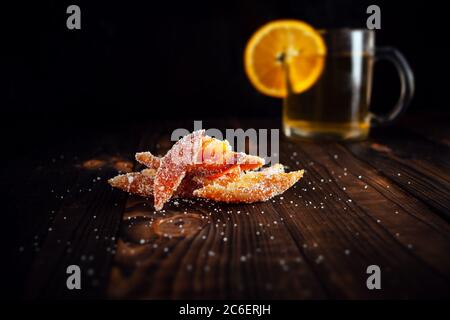 Orangenschalen in Zucker. Kandierte Früchte aus Orange. Orangefarbene Marmelade auf einem braunen Holztisch mit schwarzem Hintergrund. Tee mit Orangenscheiben. Leerumrahmt Stockfoto