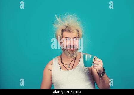 Schläfriger Kerl mit einer Tasse Kaffee. Mann im Schlafanzug mit einer Tasse auf blauem Hintergrund. Stockfoto