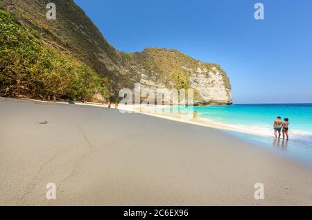 Touristen in Badeanzug zu Fuß auf T-rex Paradise Beach, eine tropische Sandbucht in hohen Klippen und einem Mangrovenwald, entlang des Indischen Ozeans in Nusa P Stockfoto