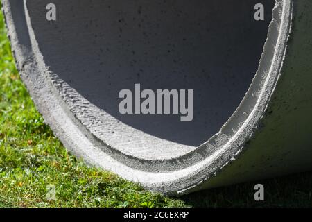 Grauer Betonring mit Schatten innen liegt auf grünem Gras, abstrakter industrieller Fotohintergrund Stockfoto