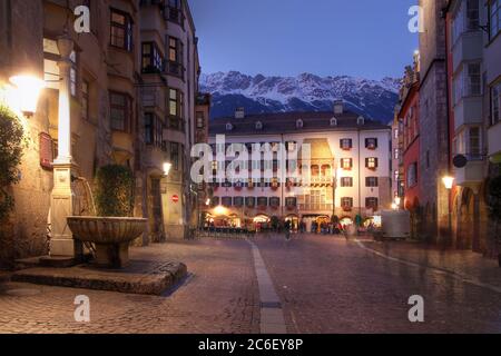 Das Goldene Dach von der Fußgängerzone Herzog-Friedrich Straße aus gesehen am Abend in Innsbruck, Österreich. Etwas frischer Schnee bedeckt die Gipfel von t Stockfoto