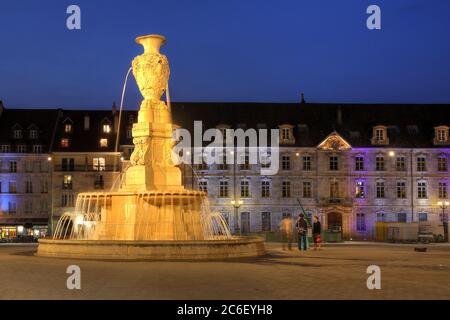 Ein Brunnen auf dem Platz der Revolution (Place de la Revolution) in Besancon, Frankreich bei Nacht mit dem städtischen Konservatorium im Hintergrund. Stockfoto