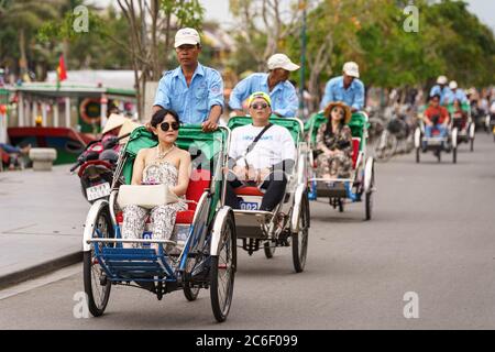 Männer transportieren Menschen mit ihrem pedalbetriebenen Taxi durch die Straßen von hoi an während des Tages Stockfoto