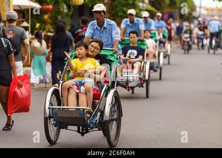 Männer transportieren Menschen mit ihrem pedalbetriebenen Taxi durch die Straßen von hoi an während des Tages Stockfoto