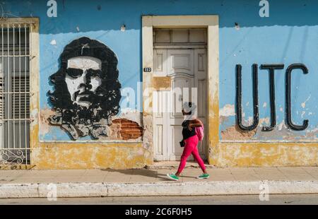 Eine Kubanerin geht an einem Bild von Che Guevara auf der Straßenseite in Trinidad, Kuba, vorbei. Stockfoto