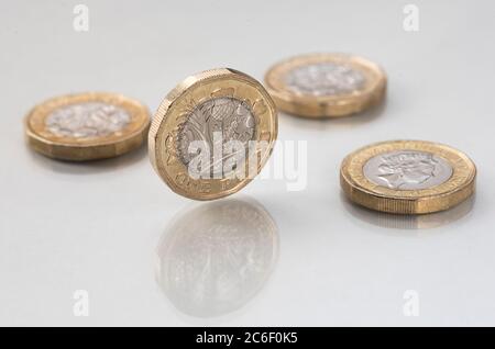 Stillleben von vier ein-Pfund-Münzen auf einem reflektierenden weißen Hintergrund. Vereinigtes Königreich / Großbritannien Sterling Währung. Stockfoto