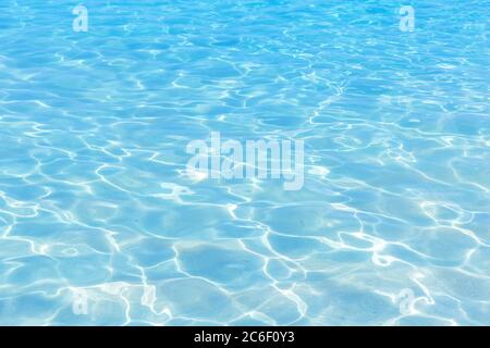 Leuchtendes blaues Wasser Welligkeit Hintergrund. Wasseroberfläche im Schwimmbad. Stockfoto