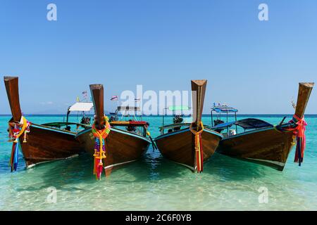 Verschiedene asiatische Boote auf türkisfarbenem Wasser an sonnigen Tagen und blauen Himmel Stockfoto