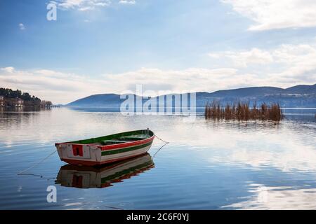 Boot mit Möwen im schönen See Orestiada gegen Berge und Kastoria Stadthintergrund. Kastoria ist eine Stadt im Norden Griechenlands. Stockfoto