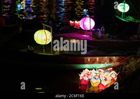 Asiatisches Boot mit farbigen chinesischen Laternen, die nachts im Wasser sein Licht reflektieren Stockfoto