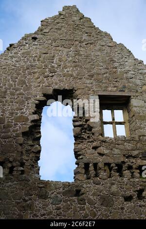 Blauer Himmel und eine flauschige Lichtwolke, die durch die alten Fenster der antiken Ruinen von Dunluce Castle in der Grafschaft Antrim, Nordirland, sichtbar ist Stockfoto