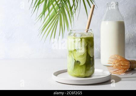 Iced Green Matcha Tee gemischt mit Eiswürfel und Milch in Latte Glas auf weiß. Stockfoto