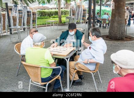 Las Palmas, Gran Canaria, Kanarische Inseln, Spanien. Juli 2020. Spanische Männer spielen zum ersten Mal seit der Aussperrung Dominos im Parque Santa Catalina in Las Palmas auf Gran Canaria. Der Park, der normalerweise ein Bienenstock von Aktivitäten ist, in dem Dominospielende und Schachspieler spielen, ist seit Beginn der Covid-Sperre im März geschlossen. Quelle: Alan Dawson/Alamy Live News Stockfoto