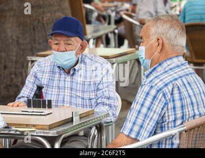 Las Palmas, Gran Canaria, Kanarische Inseln, Spanien. Juli 2020. Spanische Männer spielen zum ersten Mal seit der Aussperrung Dominos im Parque Santa Catalina in Las Palmas auf Gran Canaria. Der Park, der normalerweise ein Bienenstock von Aktivitäten ist, in dem Dominospielende und Schachspieler spielen, ist seit Beginn der Covid-Sperre im März geschlossen. Quelle: Alan Dawson/Alamy Live News Stockfoto