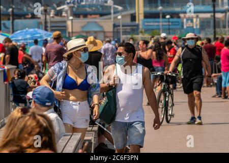 Tausende von Strandbesuchern beobachten im Allgemeinen soziale Distanzierungen, wenn sie versuchen, die Hitze und Feuchtigkeit auf Coney Island in Brooklyn in New York am Long Independence Day Wochenende, Sonntag, 5. Juli 2019 zu schlagen. (© Richard B. Levine) Stockfoto