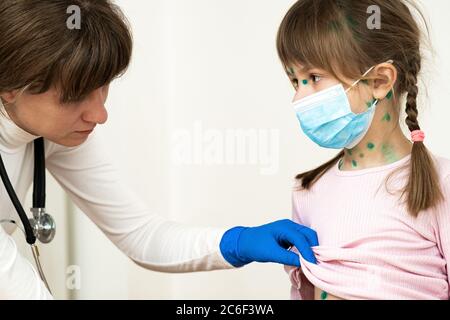 Arzt untersucht Mädchen mit grünen Ausschlägen auf Gesicht und Bauch erkrankt an Windpocken, Masern oder Röteln Virus. Stockfoto