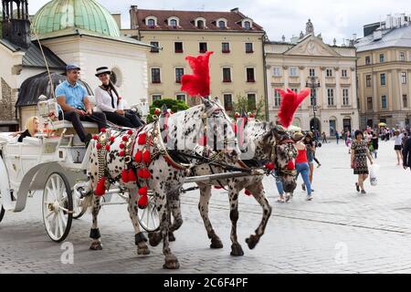 KRAKAU, POLEN - 26. Juli 2017: Pferdekutschen bringen Touristen zum Sightseeing in der Altstadt Marktplatz von Krakau, Polen Stockfoto